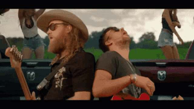 a man in a cowboy hat is playing a guitar