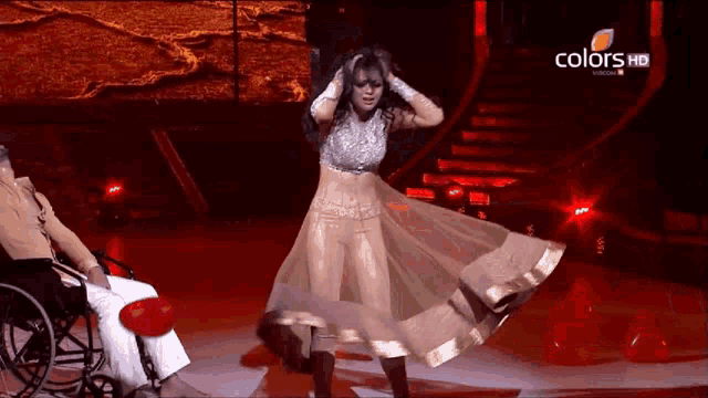 a woman dancing on a stage with a man in a wheelchair watching