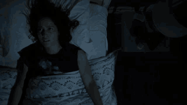 a woman is laying on a bed with a pillow on her face