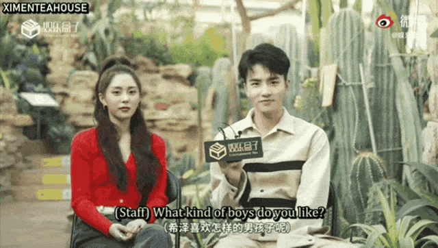 a man and a woman are sitting in front of a sign that says ' staff what kind of boys do you like ? '