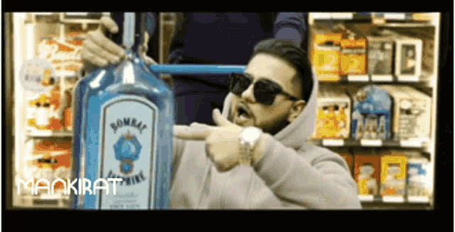 a man is pointing at a large bottle of bombay gin