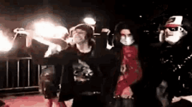 a group of people are standing next to each other in a dark room holding fireworks .