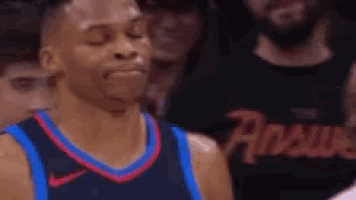 a basketball player is sitting in the stands during a game and making a face .