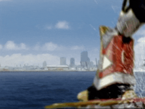 a blurred image of a person standing in front of a body of water and a city skyline