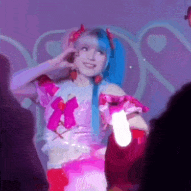 a woman in a pink and blue costume is smiling and holding a light
