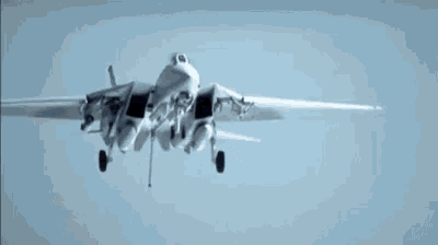 a fighter jet is flying through a blue sky with its landing gear down .