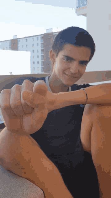 a young man in a black shirt giving a thumbs up sign