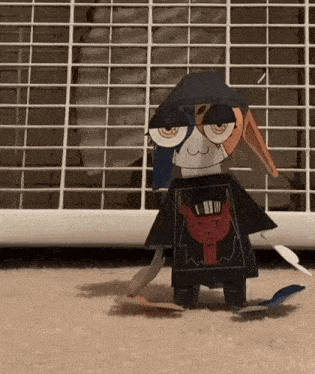 a paper doll is wearing a black shirt with a red devil on it .