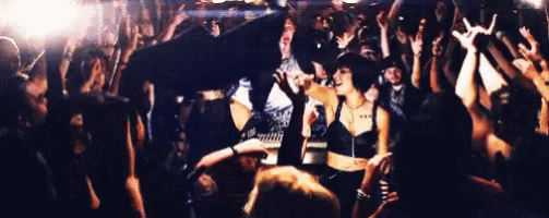 a woman is singing into a microphone in front of a crowd .