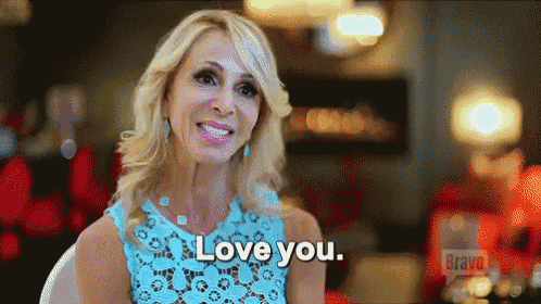 a woman in a blue dress is sitting in a chair and smiling while saying `` love you '' .