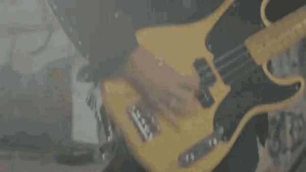 a man is playing a bass guitar in a dark room with smoke coming out of it .