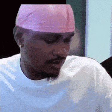 a man wearing a white shirt and a pink headband looks down