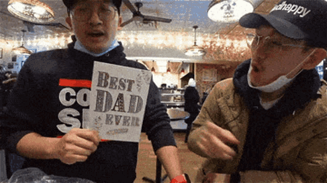 a man holding up a sign that says best dad ever