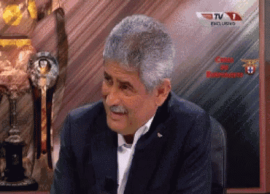 a man sitting in front of a tv screen that says tv 1 exclusive