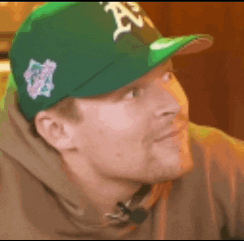 a man wearing a green baseball cap with the letter a on it