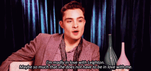 a man in a suit is sitting in front of a curtain and talking about being madly in love with leighton .