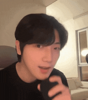 a man in a black shirt is holding a cell phone in his hand