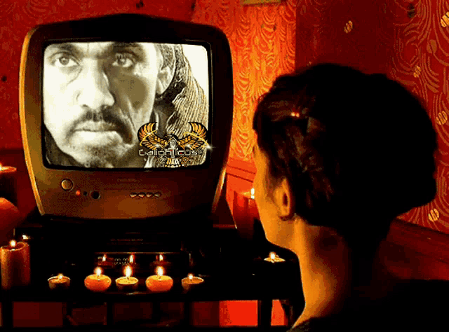 a woman is looking at a tv screen with a picture of a man on it and the words egypticon on it