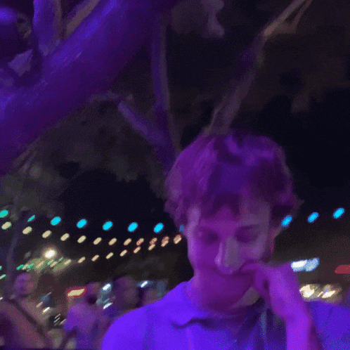 a man in a purple shirt is smiling in front of a crowd