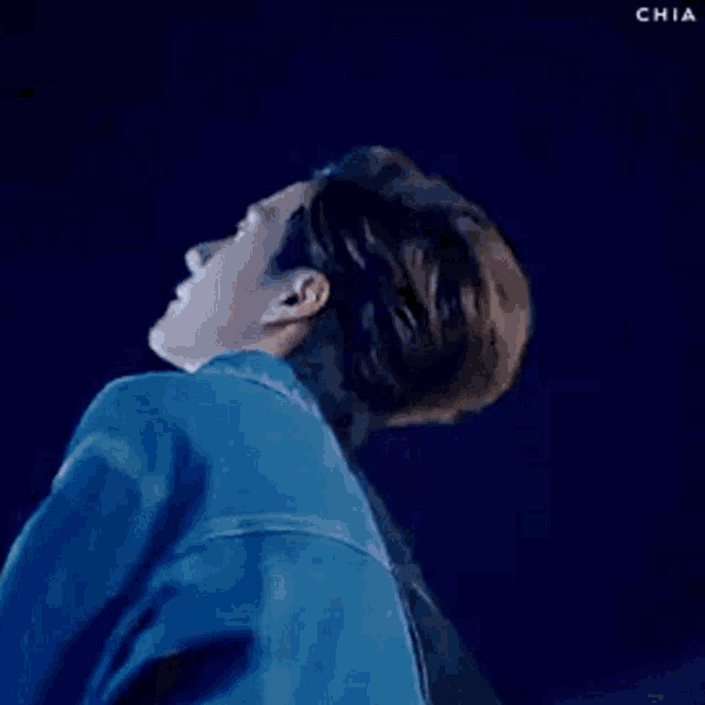 a man in a white shirt and a blue jacket is dancing in front of a blue background .