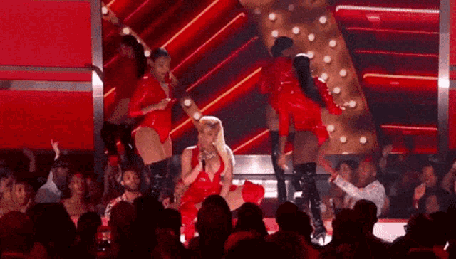 a woman in a red outfit is singing into a microphone on a stage
