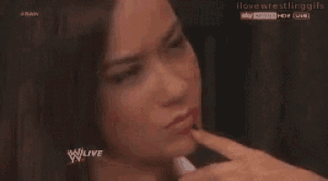 a woman is making a funny face and pointing at her face .