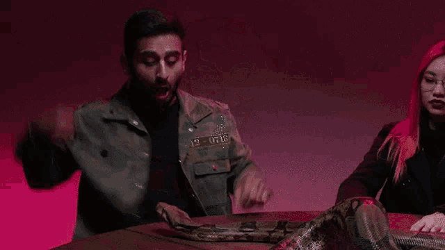 a group of people sit around a table with a large snake on it