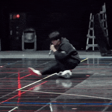 a person is kneeling down on a stage with a microphone in their hand