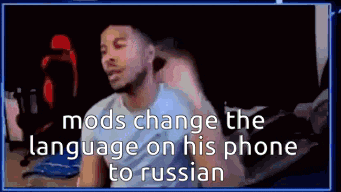 a man is sitting in front of a computer screen with the words `` mods change the language on his phone to russian ''