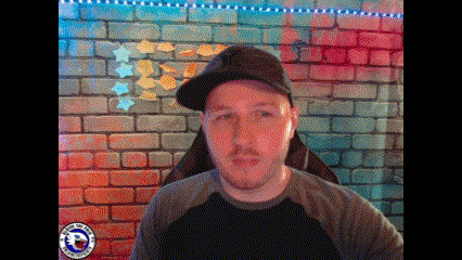 a man wearing a hat is sitting in front of a colorful brick wall .