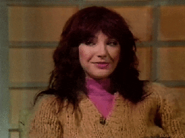 a woman with red hair is wearing a sweater and a pink shirt