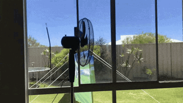 a fan is turned on in front of a window with a tent in the background