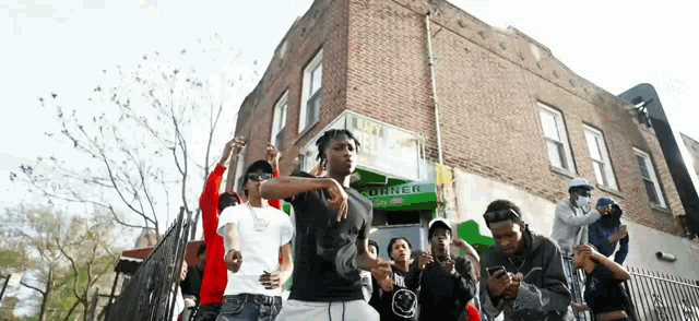 a group of young men are standing in front of a building that says corner