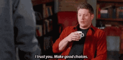 a man in a red shirt is sitting in a chair holding a cup of coffee and talking to someone .