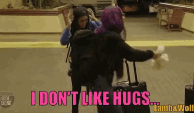 a woman with purple hair is hugging another woman and says i don 't like hugs lamb & wolf