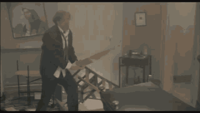 a man in a suit and tie is holding a large piece of wood in a room