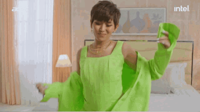 a woman in a green jacket is dancing in a bedroom with an intel logo