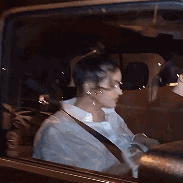 a woman in a white shirt is sitting in a car