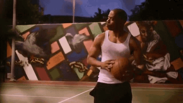 a man in a white tank top is holding a basketball on a basketball court