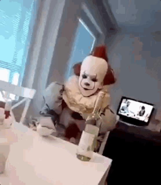 a clown is sitting at a table with a bottle of wine in his hand .