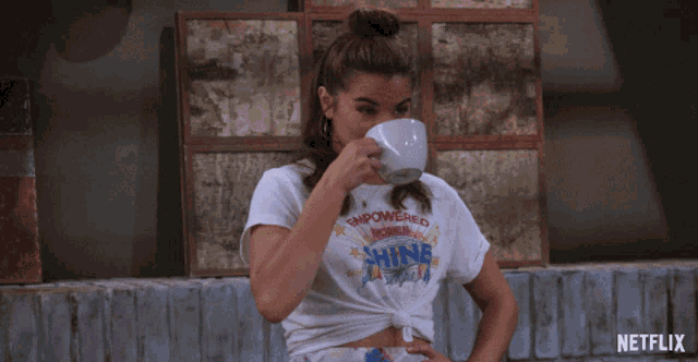 a woman drinking from a cup with a t-shirt that says empowered women shine