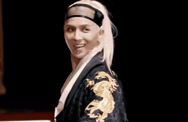 a man wearing a black robe with a dragon on the sleeve