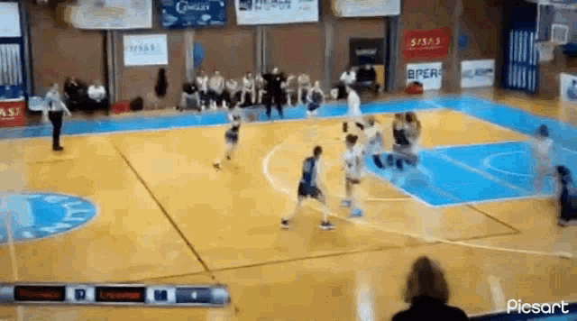 a basketball game is being played on a court with a scoreboard in the background .