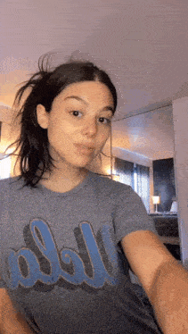 a woman is taking a selfie in front of a mirror while wearing a gray t-shirt with the word doll on it