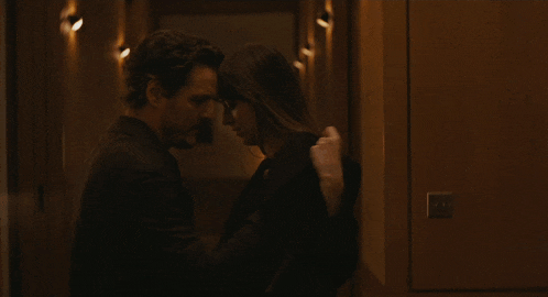 a man and a woman are kissing in a dark hallway
