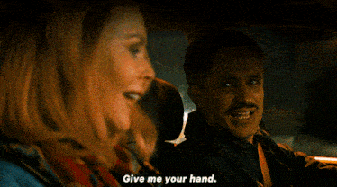 a man and woman are in a car and the woman is saying give me your hand