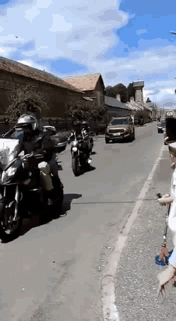 a group of motorcycle riders are riding down a street