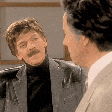 a man with a mustache is wearing a leather jacket