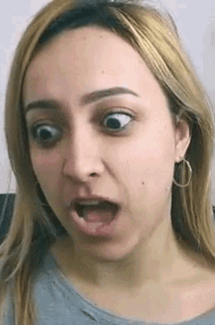 a woman is making a funny face with her mouth open and a surprised look on her face .