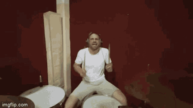 a man wearing headphones is playing a drum set in a bathroom .